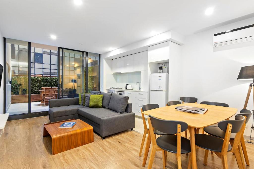 ein Wohnzimmer mit einem Tisch und einem Sofa in der Unterkunft Carlton Delight - Patio Abode near Queen Vic Market in Melbourne
