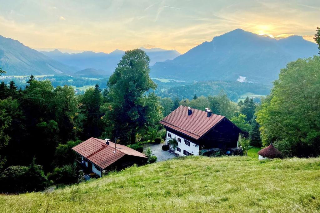 dos casas en una colina con montañas en el fondo en nock her berge, en Marquartstein