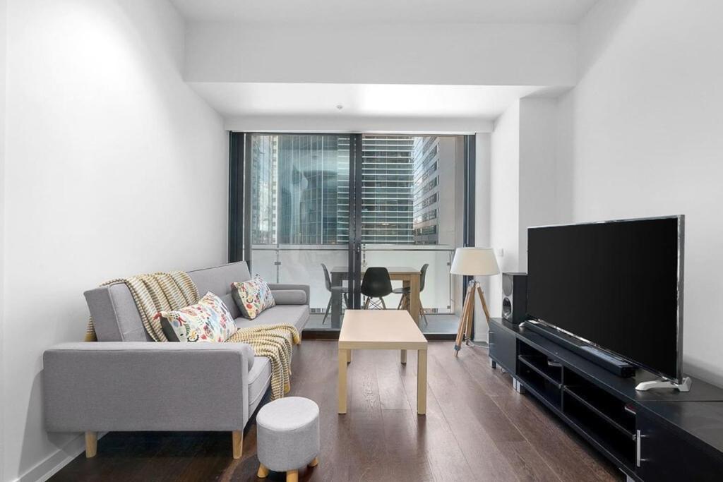 een woonkamer met een bank en een flatscreen-tv bij CBD Serenity with Luxury Rooftop Pool and Parking in Melbourne
