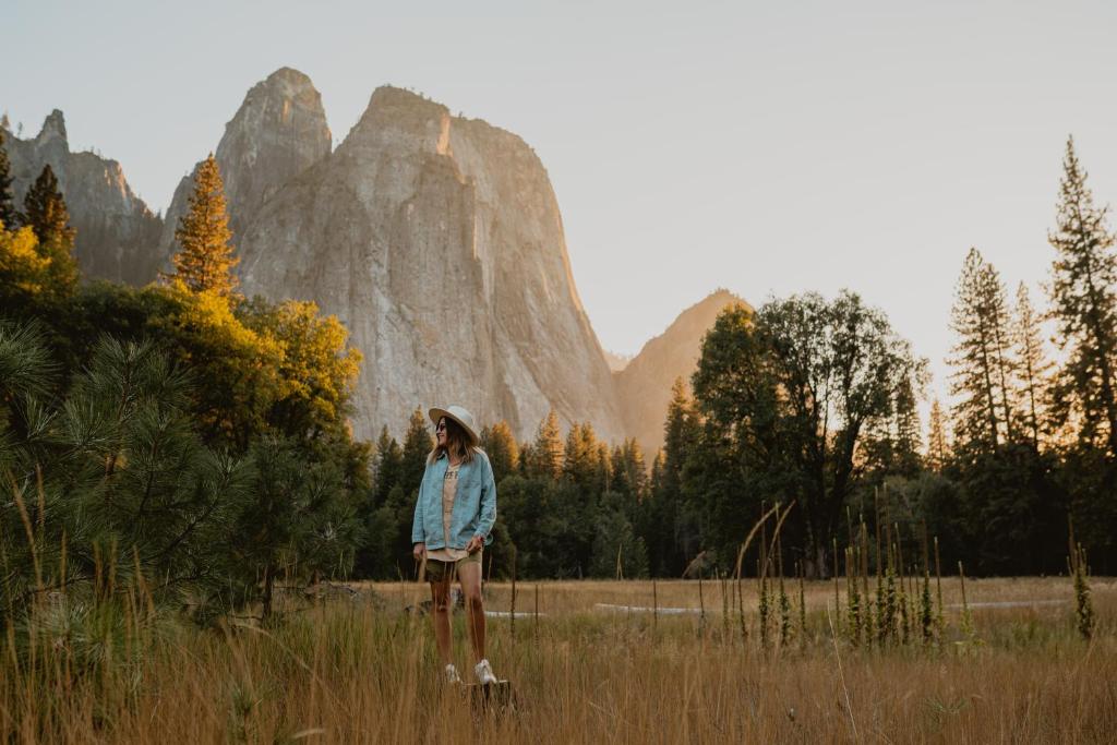 a woman standing in a field with mountains in the background at Yosemite Expedition Chalet with bbq by Casa Oso in Oakhurst
