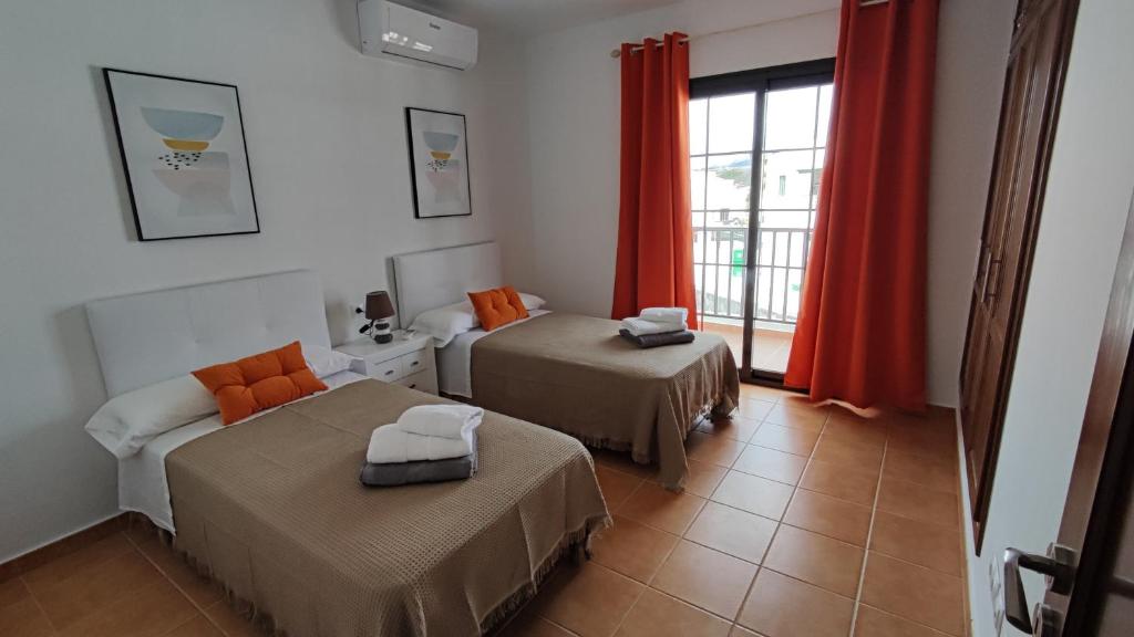a room with two beds and a window with red curtains at Villa Tingafa in Yaiza
