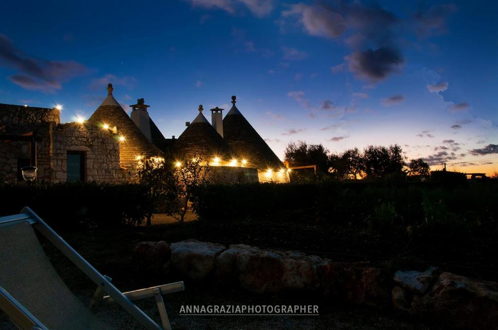 Una vista nocturna de una casa con luces. en Trulli Il Castagno, en Martina Franca