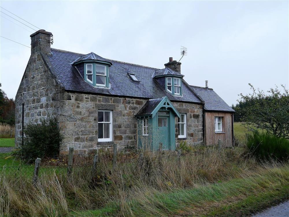 an old stone house with a green door at Bogroy in Aberlour