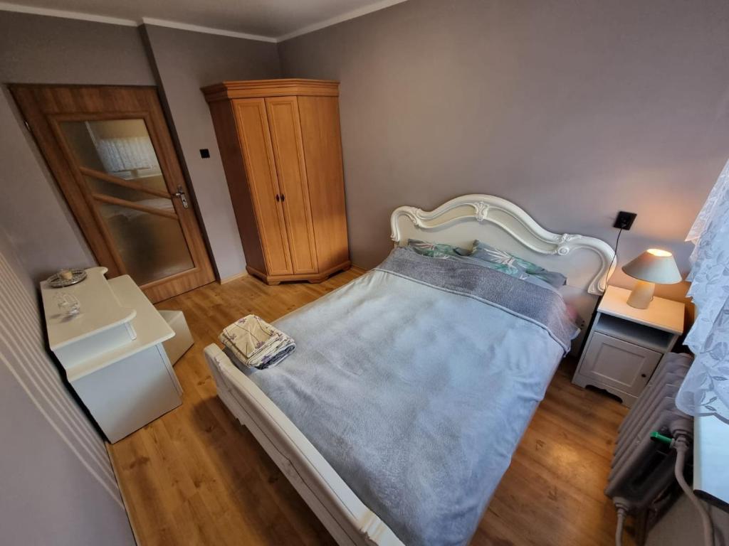 a small bedroom with a bed and a wooden floor at Wczasy-Leba in Wicko