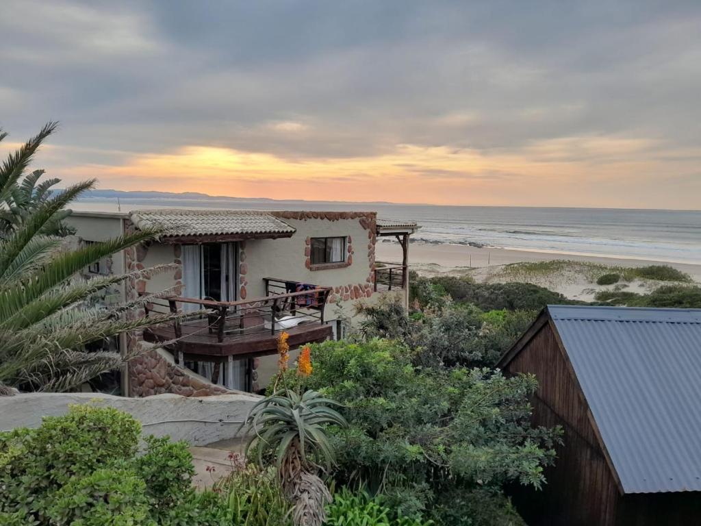 a house on the beach with the ocean in the background at Island Vibe Jeffreys Bay in Jeffreys Bay