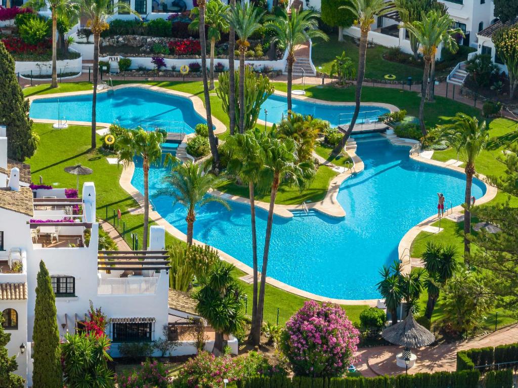 an aerial view of a resort pool with palm trees at VACATION MARBELLA I Aldea Blanca, Luxury Duplex, Sea View, Walking Distance to Puerto Banus in Marbella