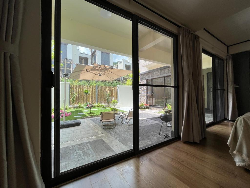 大理市にあるDalifornia Courtyard Retreatのパティオにつながるガラスのスライドドアが付いた客室です。