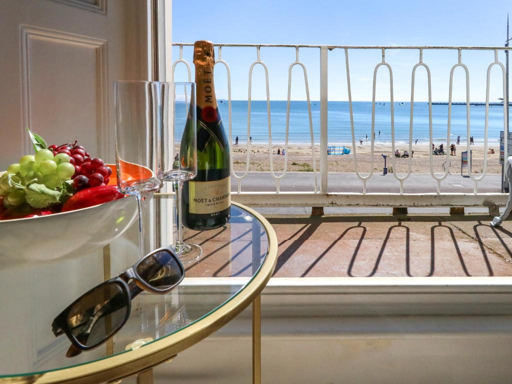 a glass table with a bottle of wine and a bowl of fruit at 123 On The Sea in Weymouth
