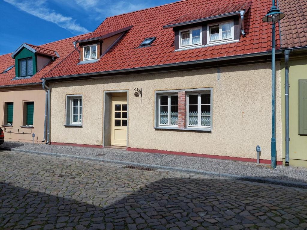 a house with a red roof on a cobblestone street at Holiday Home in idyllic Ziesar near the Natuurpark in Gladau