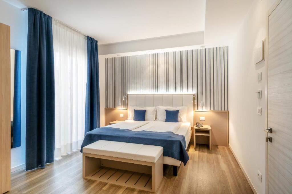 a bedroom with a large bed with blue sheets and blue curtains at International Beach Hotel in Caorle