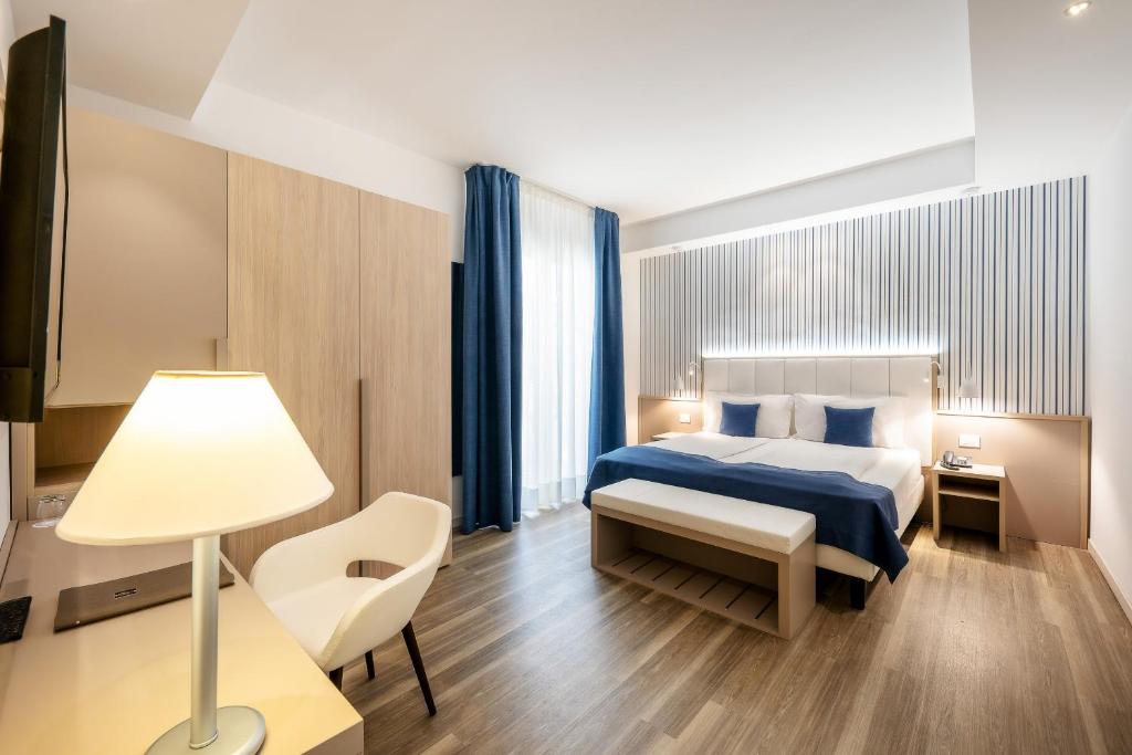 a hotel room with a bed and a desk and a lamp at International Beach Hotel in Caorle