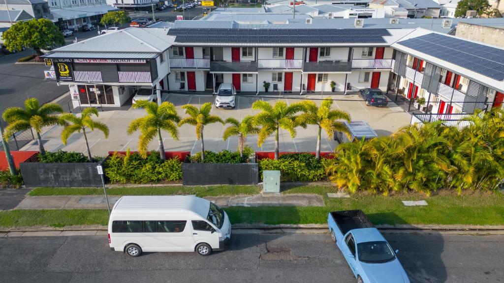 a white van parked in a parking lot with palm trees at Citywalk Motor Inn in Rockhampton