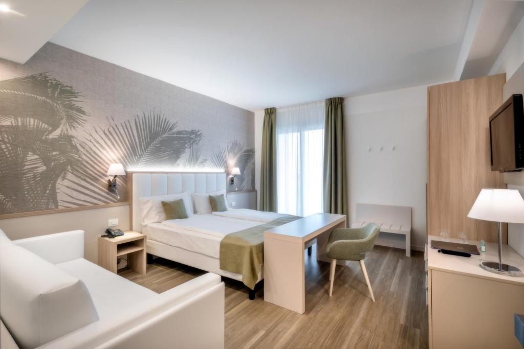 a bedroom with a bed and a desk and a couch at International Beach Hotel in Caorle