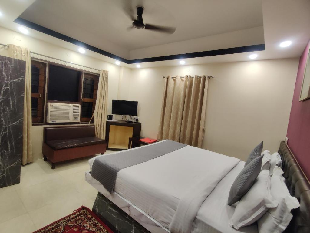 a bedroom with a bed and a couch and a television at Hotel Swastik Regency in Siliguri