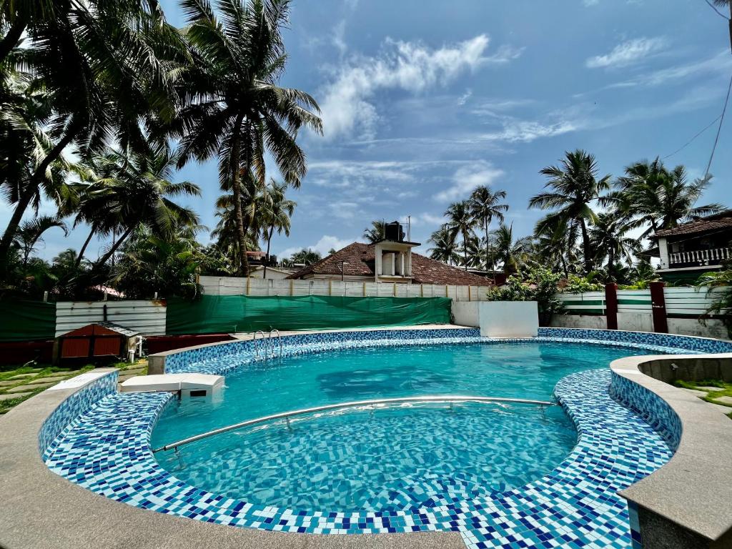a swimming pool in a yard with palm trees at Red Sea Beach Resort in Anjuna