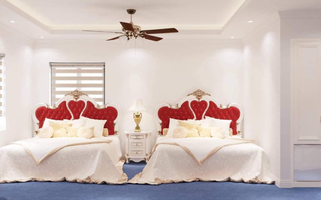 a white bedroom with two beds with red headboards at Hoang Gia Hotel Ha Noi Capital in Hanoi