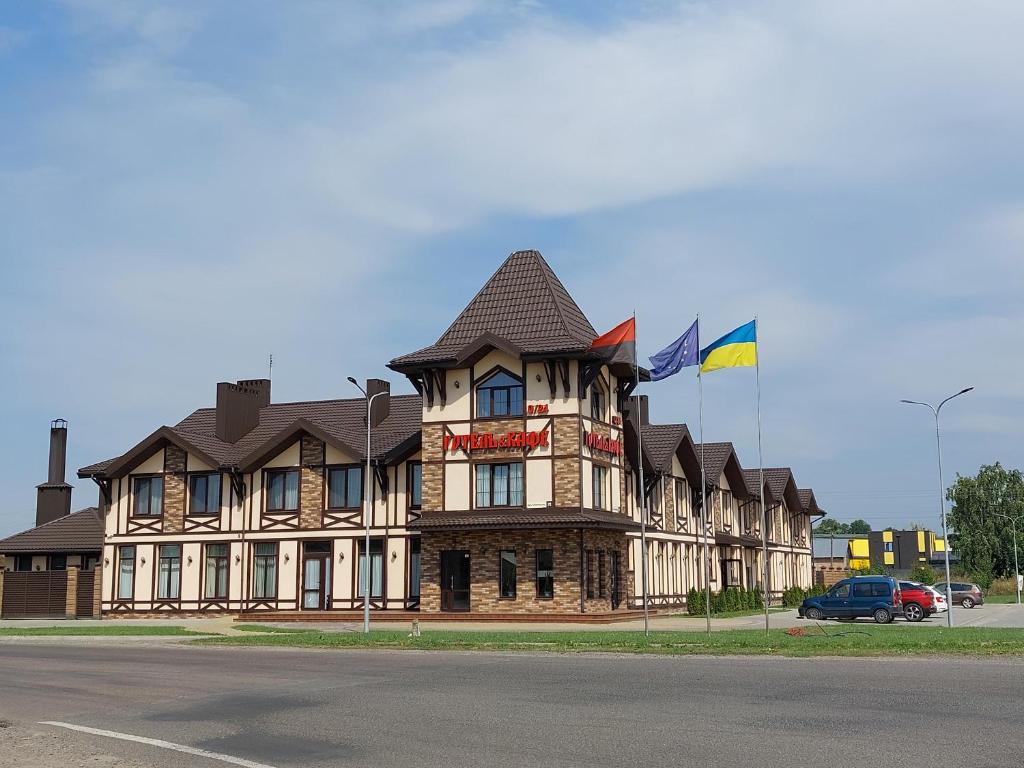 duży budynek z dwoma flagami na górze w obiekcie Ліжниця w mieście Radekhov