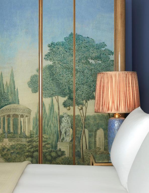 a painting on a wall next to a bed with a lamp at Broadwick Soho in London