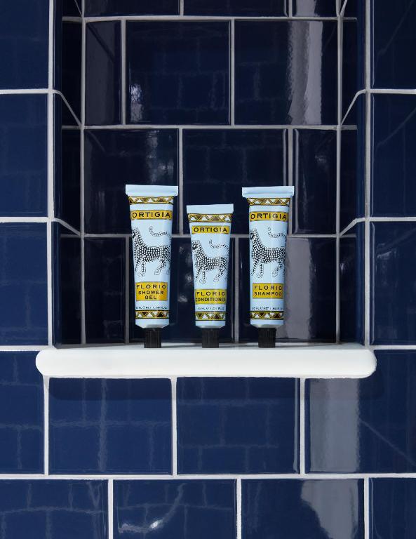 a shelf with four cups on it in front of a tiled wall at Broadwick Soho in London