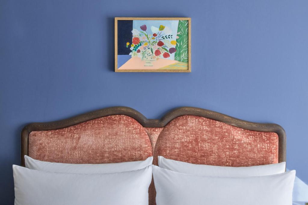 a bed with a blue wall with a picture at Broadwick Soho in London