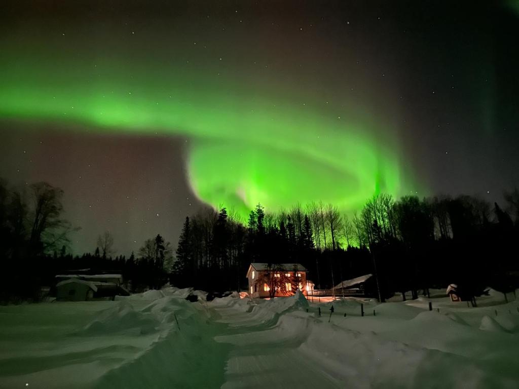 an aurora over a house in the snow at night at Hassela Villa in Hassela