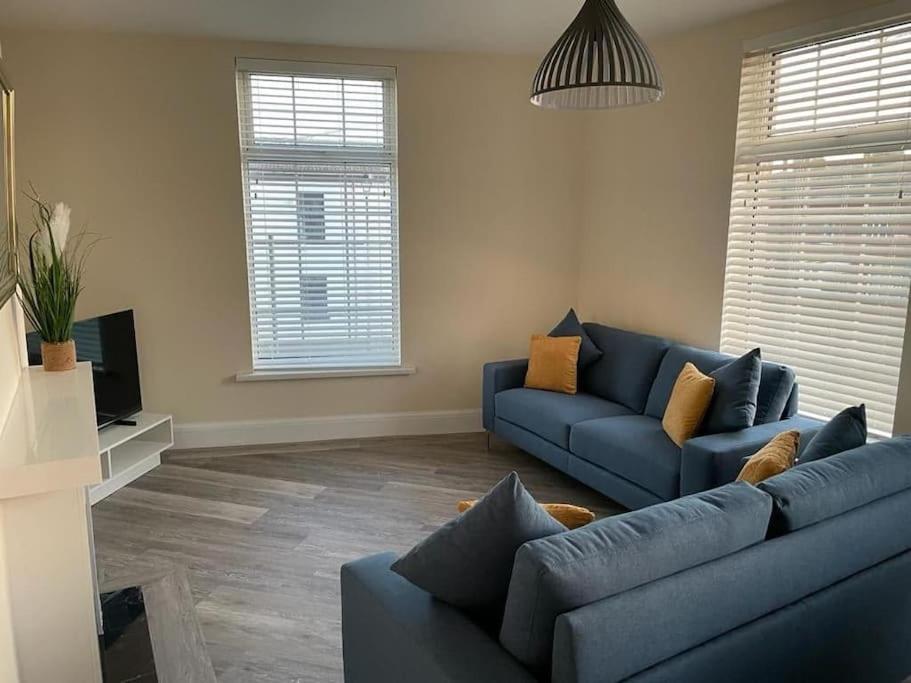 a living room with two blue couches and a tv at Lighthouse View - Lovely 3 bed 1st floor apartment in Fleetwood