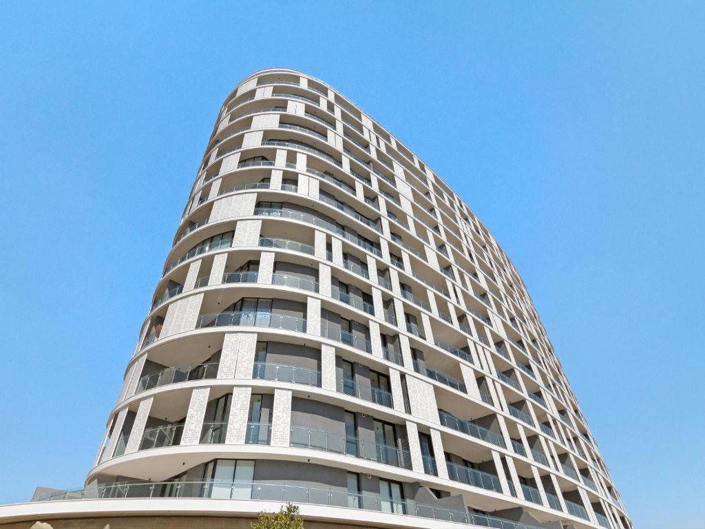 un grand immeuble d'appartements blanc avec un ciel bleu dans l'établissement Ellipse Waterfall 3902, à Midrand