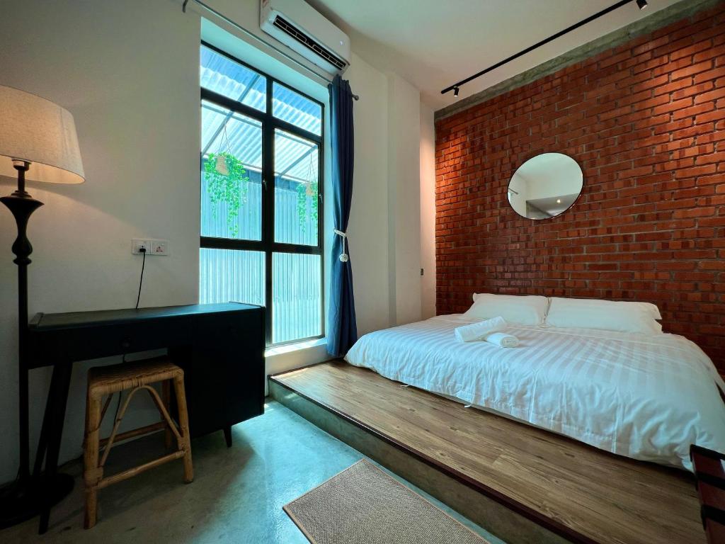 怡保的住宿－DoSomething Guest House 8，一间卧室设有砖墙、一张床和一张书桌
