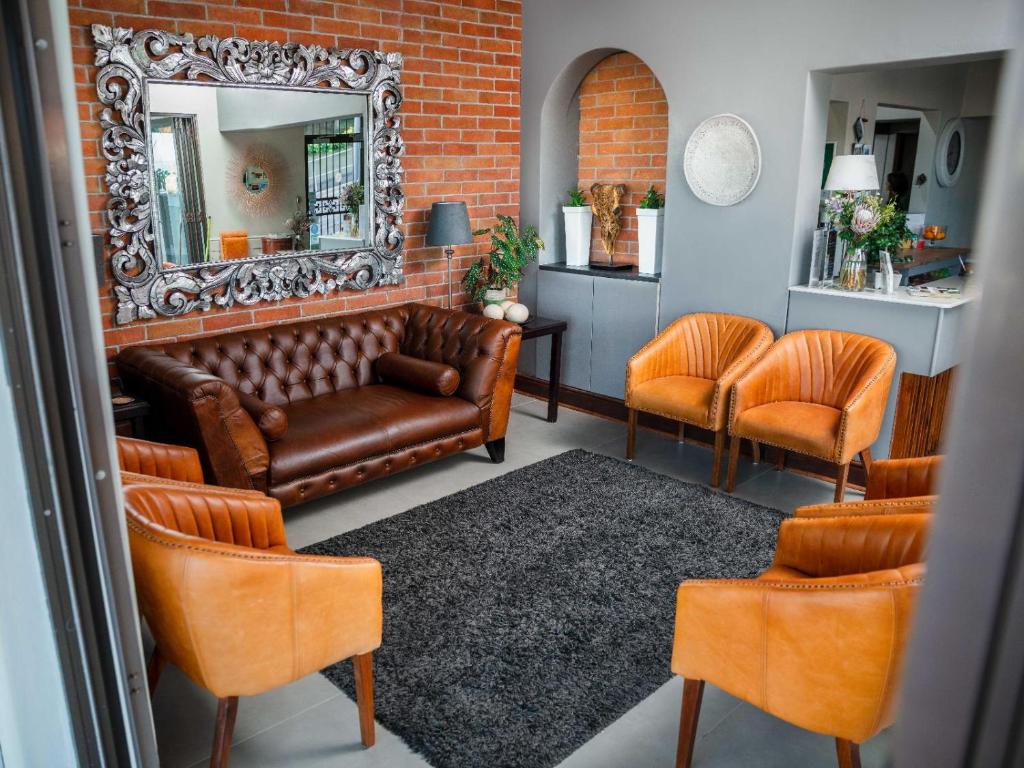 uma sala de estar com um sofá, 2 cadeiras e um espelho em Leeuwenzee Guesthouse em Cidade do Cabo