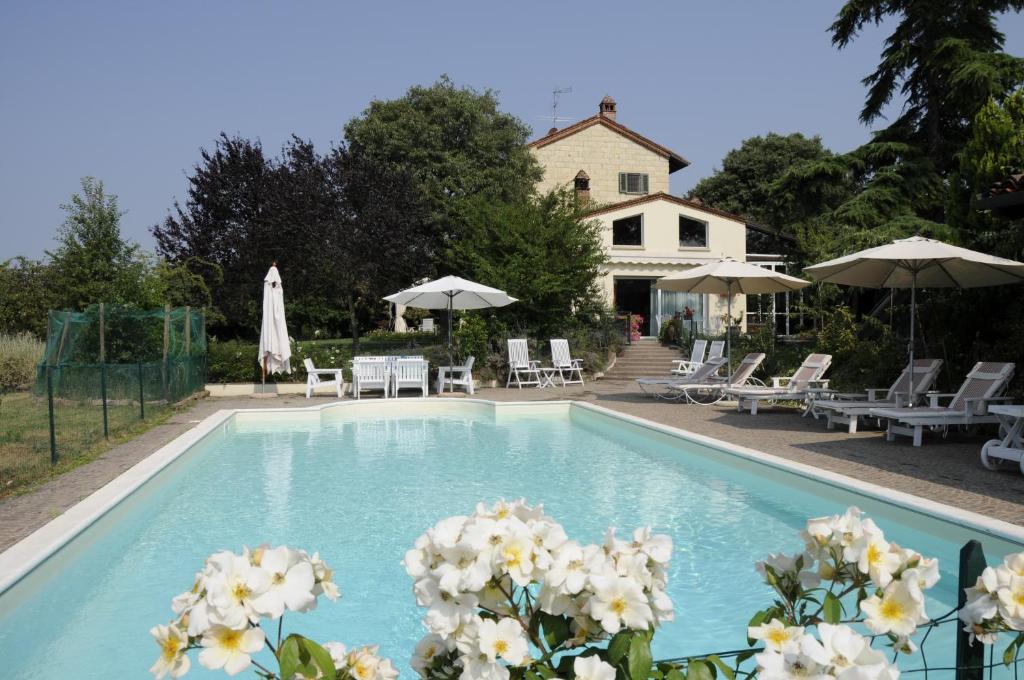 a swimming pool with white flowers in front of a house at Cascina Manu in Rosignano Monferrato