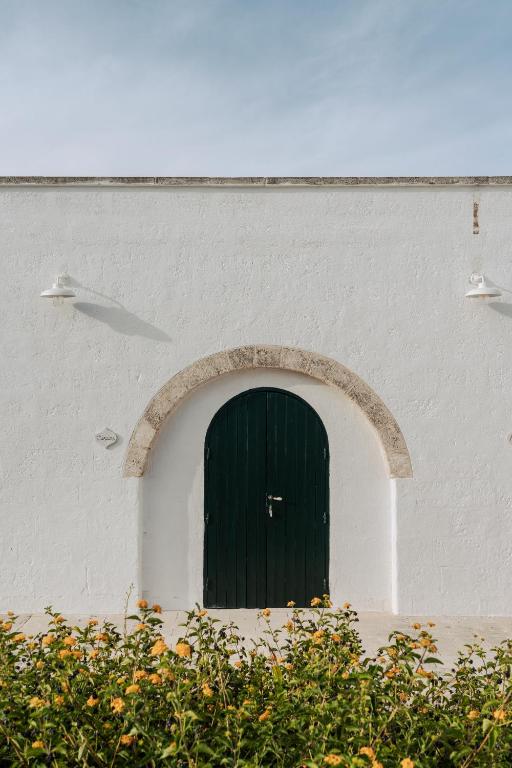 a white building with a green door in it at Masseria Gorgognolo in Ostuni