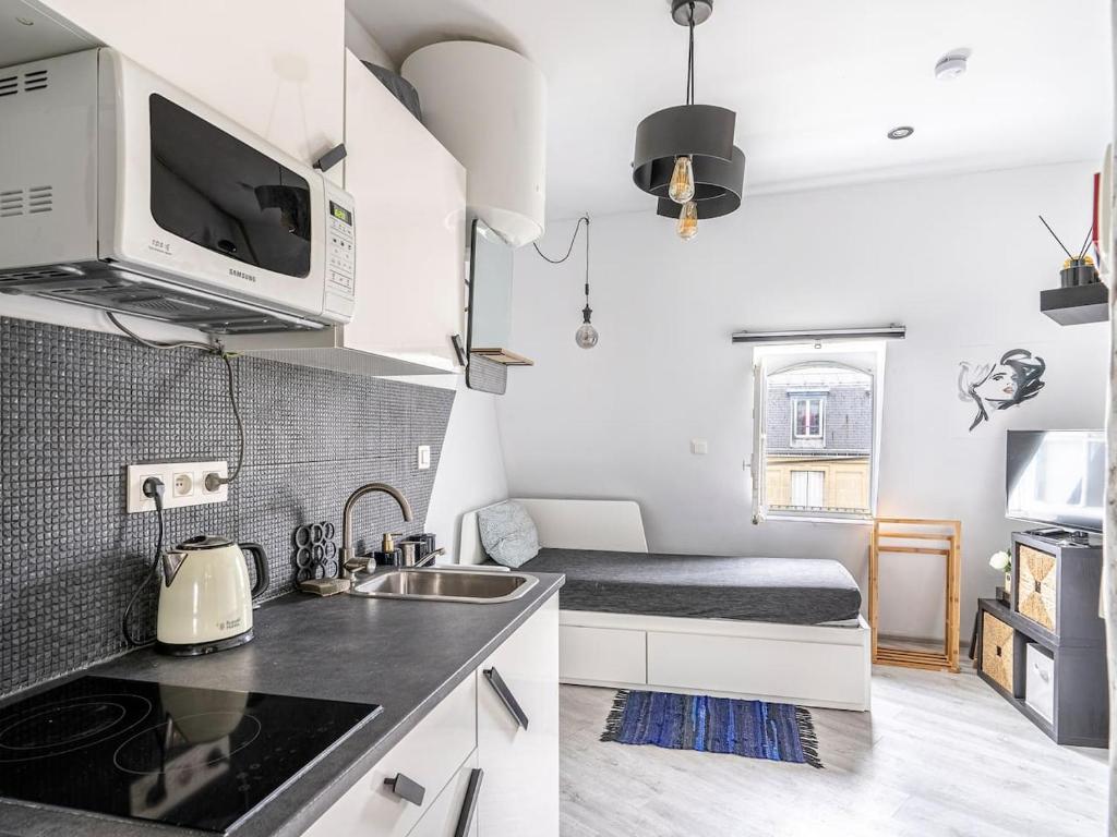 une petite cuisine avec un évier et un lit dans l'établissement Paris Dream Apart Nord, à Paris