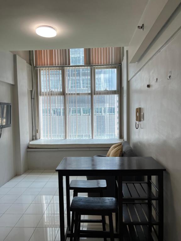 a dining room with a table and chairs and a window at unit 1827 Eton Emerald Loft ortigas , pasig city in Manila