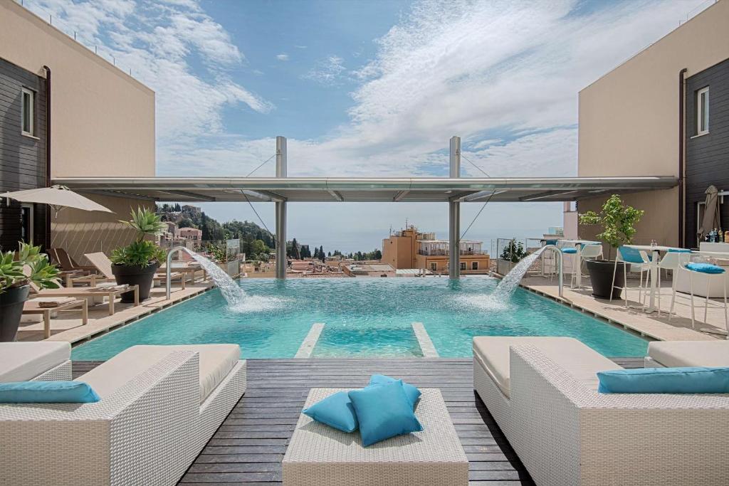 una piscina con almohadas azules en un edificio en NH Collection Taormina, en Taormina