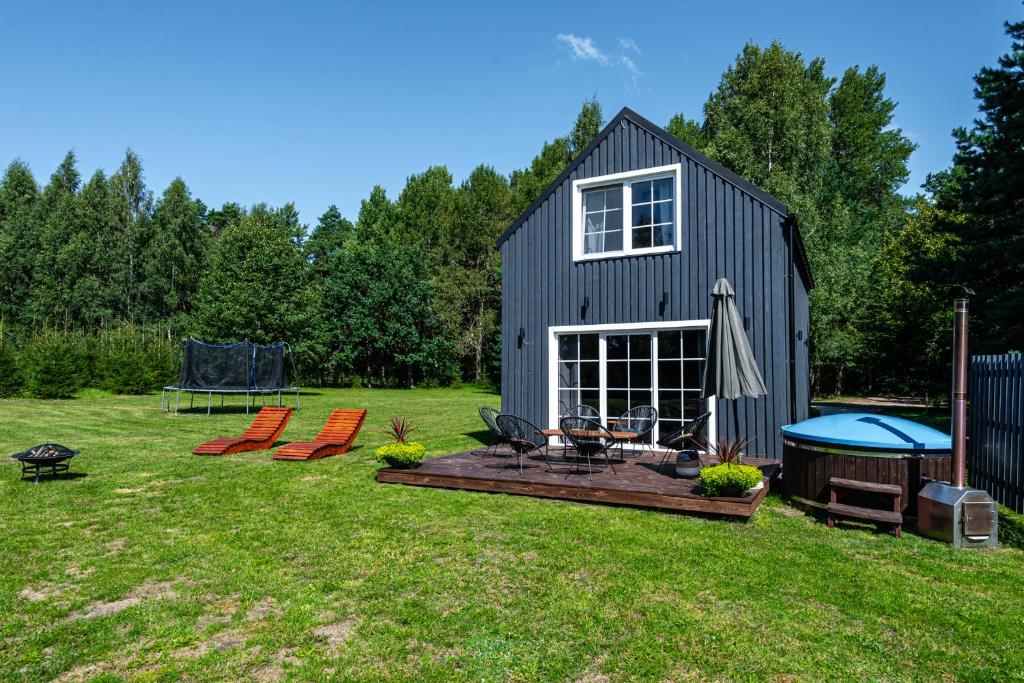 um quintal com um barracão preto com uma mesa e cadeiras em Sodyba pas Brolius - Mažasis Namelis - Entire Barn House 85m2 em Priekulė
