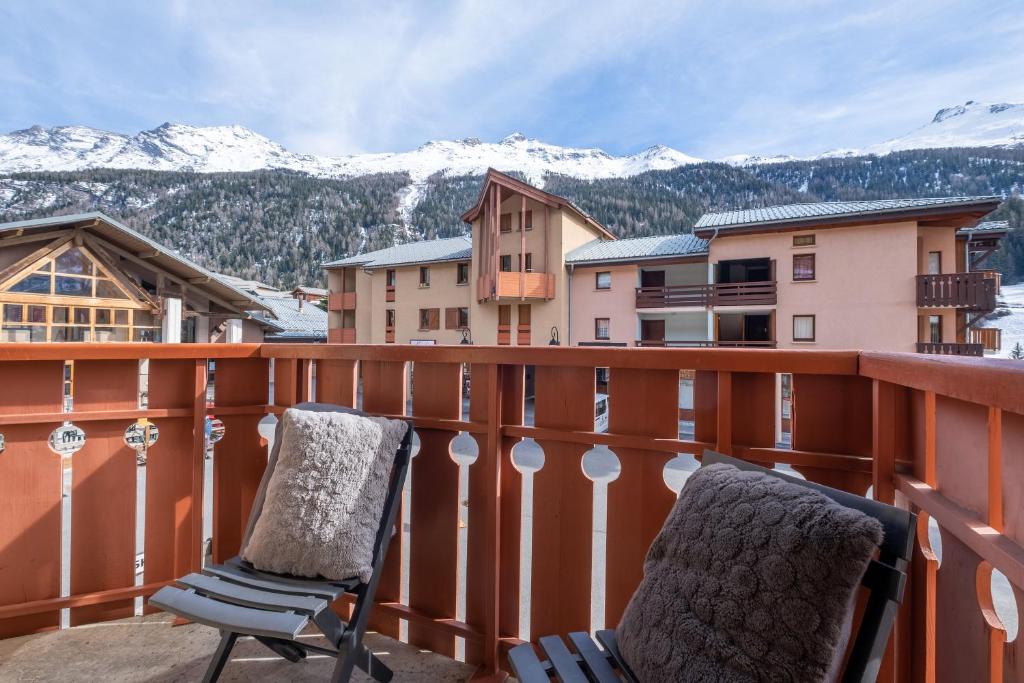 two chairs sitting on a balcony with snow covered mountains at VVF Val-Cenis Haute-Maurienne in Lanslevillard