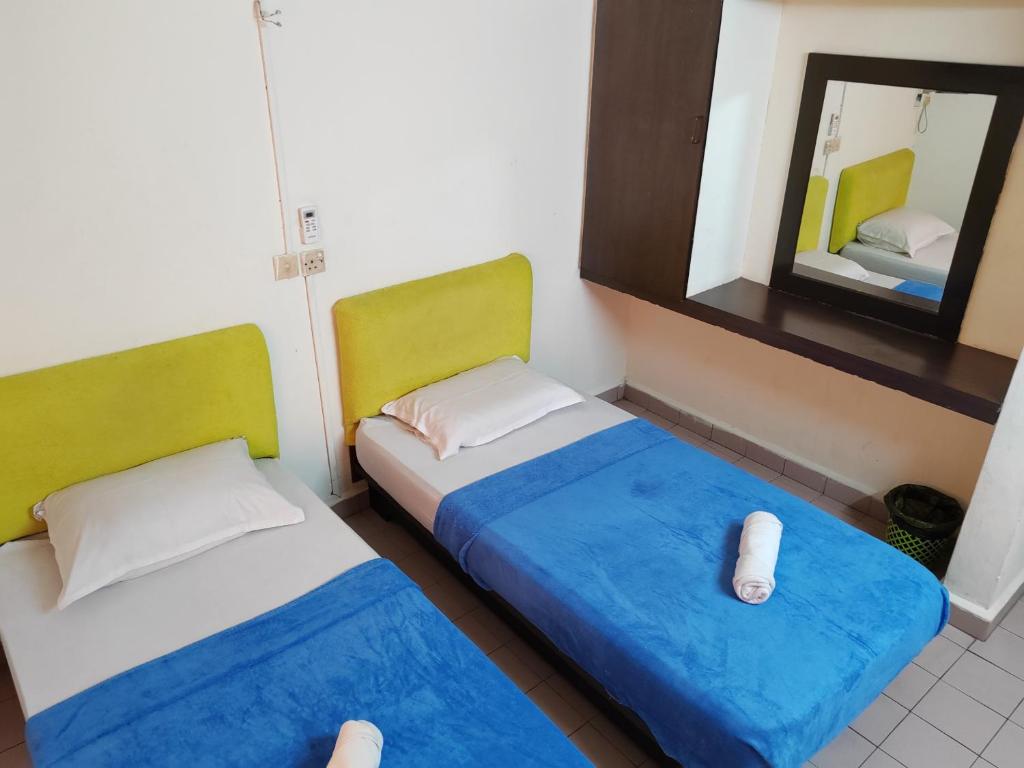 2 letti in una piccola stanza con specchio di Hotel Kenangan a Kota Bharu