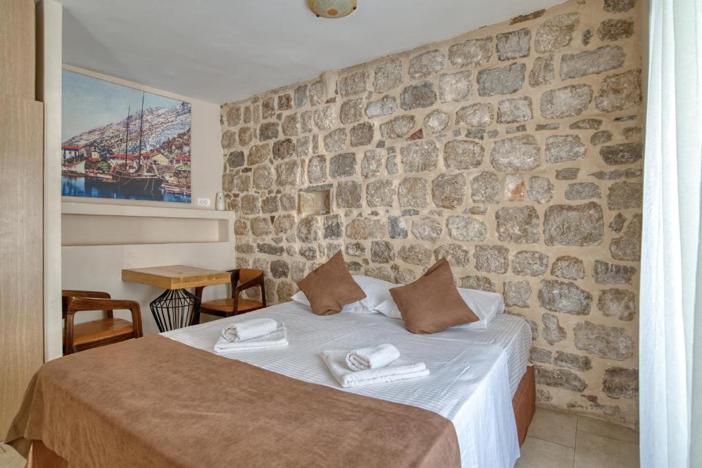 a bed in a room with a stone wall at Hotel Rendez Vous in Kotor