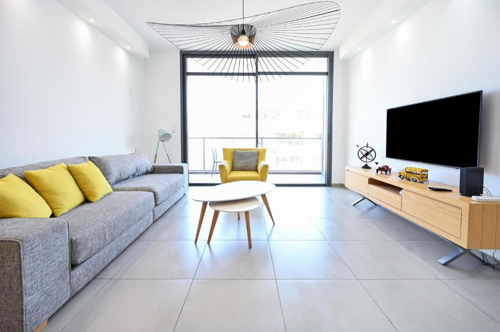 a living room with a couch and a tv at Colorful 3BR with MAMAD by HolyGuest in Tel Aviv