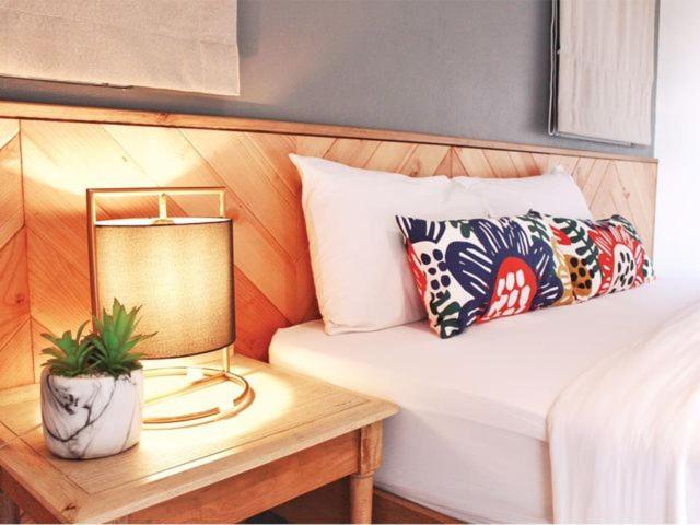 een bed met een tafel met een lamp en een kussen bij The Finn Hotel / เดอะฟินน์โฮเทล in Ban Liap