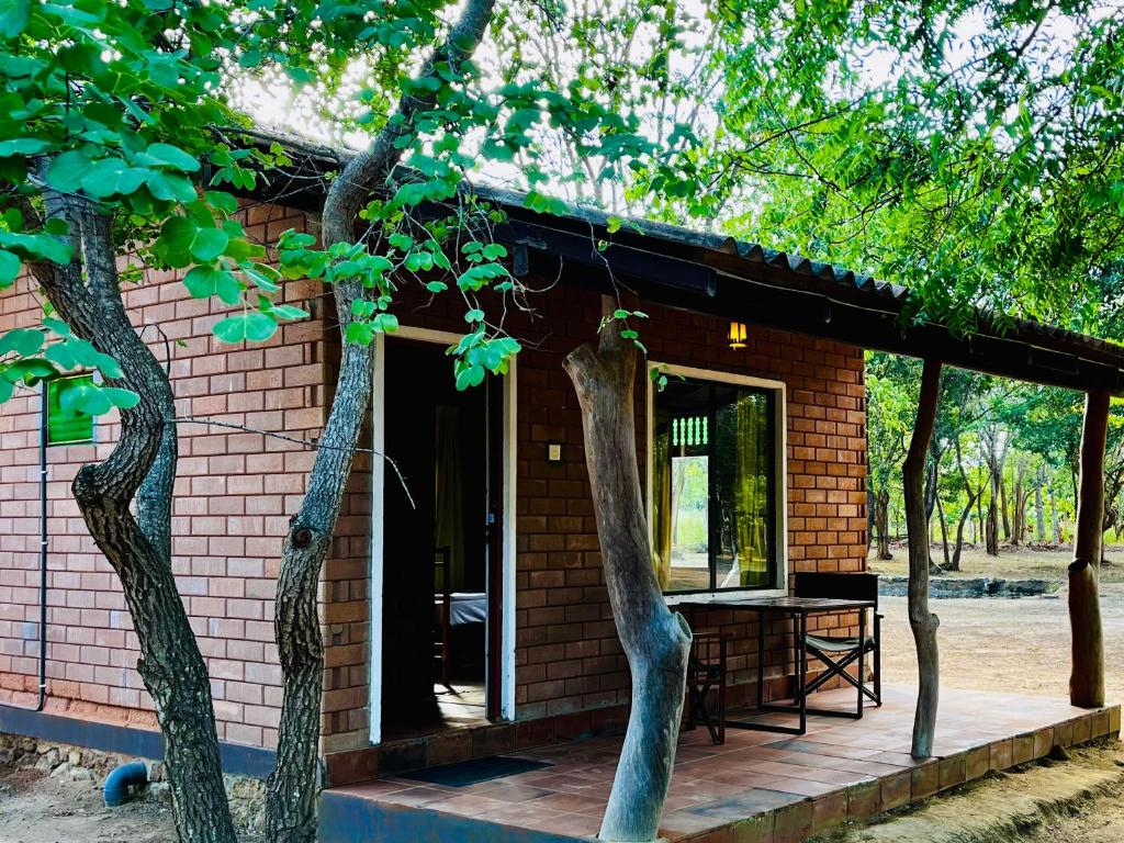 una pequeña casa de ladrillo con porche de madera en Funky Leopard Safari Lodge Bordering Yala National Park, en Kataragama