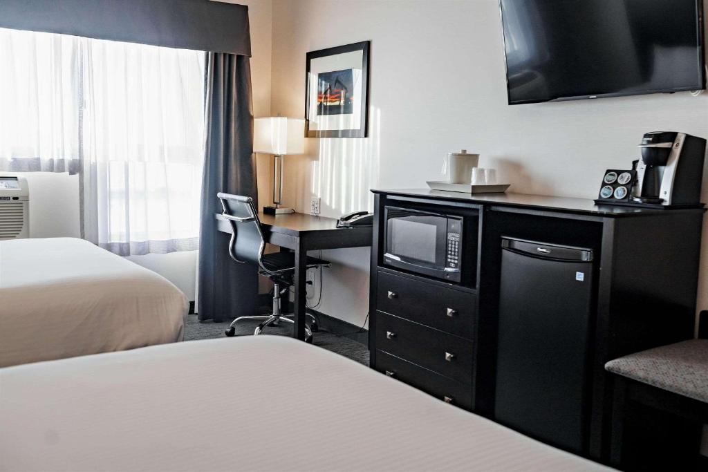 ein Hotelzimmer mit einem Bett und einem Schreibtisch mit einem TV in der Unterkunft Park Inn by Radisson Edmonton Airport in Leduc