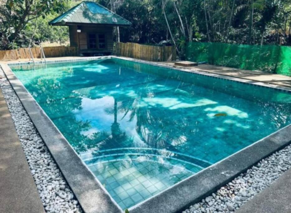 una piscina de agua azul y un cenador en Chaweang cozy house 1 km.Lotus, en Ban Ko Khwan
