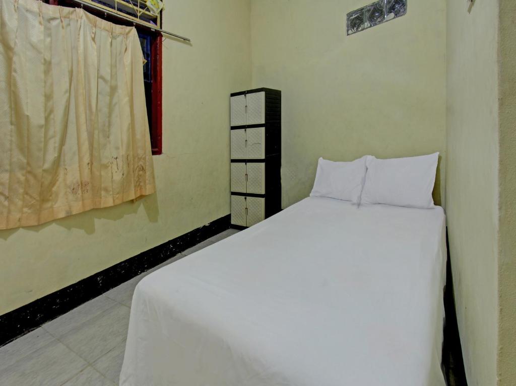 1 dormitorio con cama blanca y ventana en SPOT ON 92882 Penginapan 3 Bersaudara, en Kuta Lombok