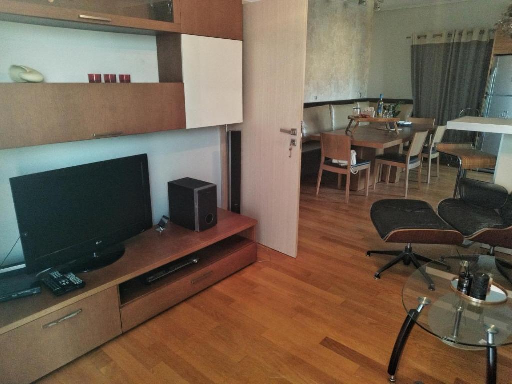 ein Wohnzimmer mit einem Flachbild-TV und einem Tisch in der Unterkunft Aris Apt in Karystos