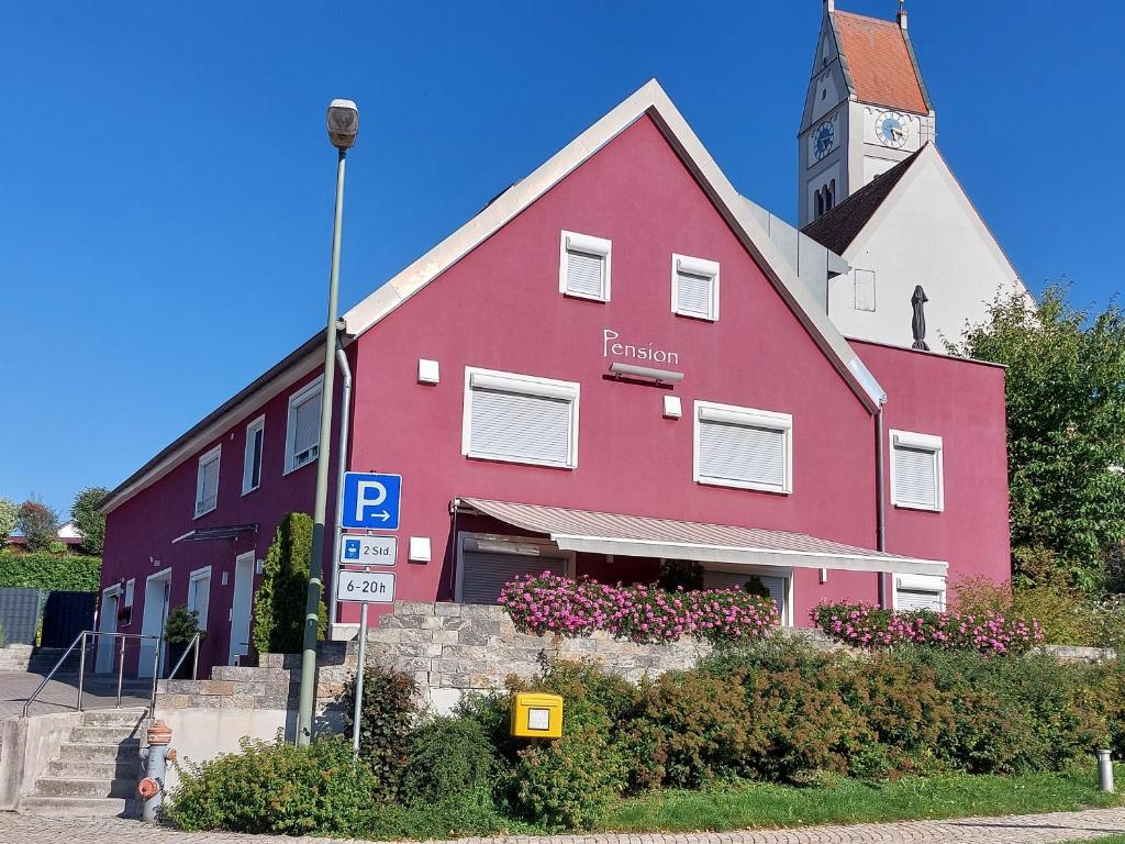 un edificio rojo con una torre de reloj encima en Pension am Kirchberg, en Wehringen