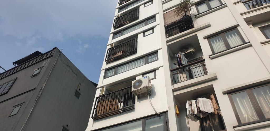 a tall white building with balconies and a clock on it at Era Apartment Đông Tác in Hanoi