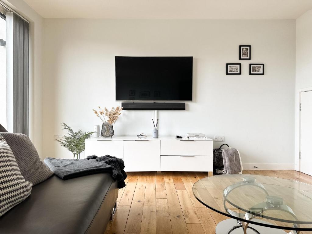 a living room with a couch and a tv on a wall at Luxury 3 Bedroom Apt. Leeds Centre in Leeds
