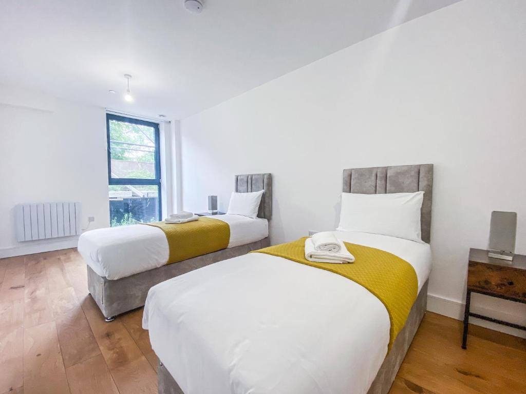a bedroom with two beds and a window at Heathrow Airport Apartments by Elegance Living in Hounslow
