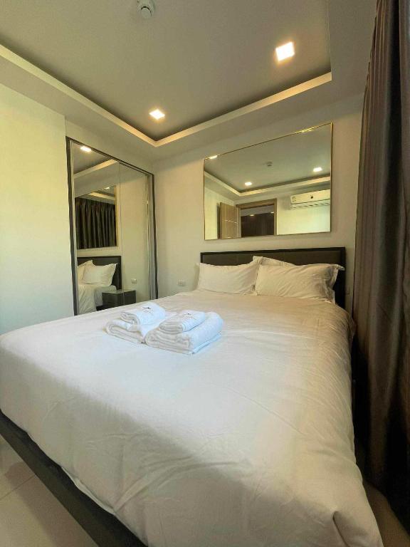 Hotel Arcadia beach continental, a bedroom with a large white bed with a mirror at Arcadia beach continental in Pattaya South